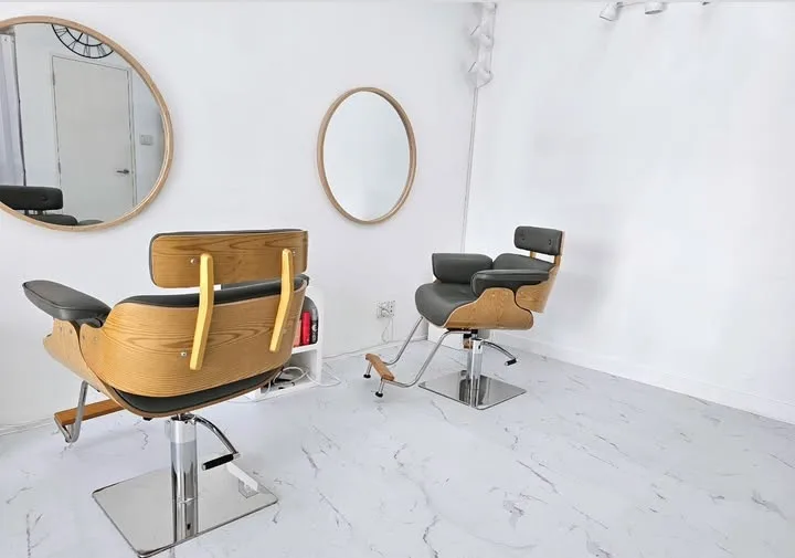 Inside Emma Hair Stylist: two wood-and-black styling chairs and round mirrors on a bright white floor