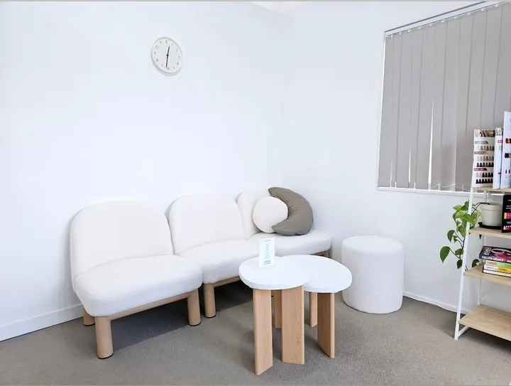 The bright waiting area at Emma Hair Stylist, with a white sofa and a small round table