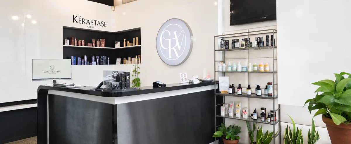 The reception desk at Groove Hair, with a Kérastase product shelf and the salon's monogram on the wall