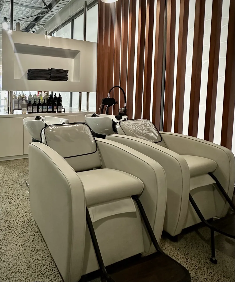 Two reclining wash basins against a timber slat wall in the head spa area at Groove Hair